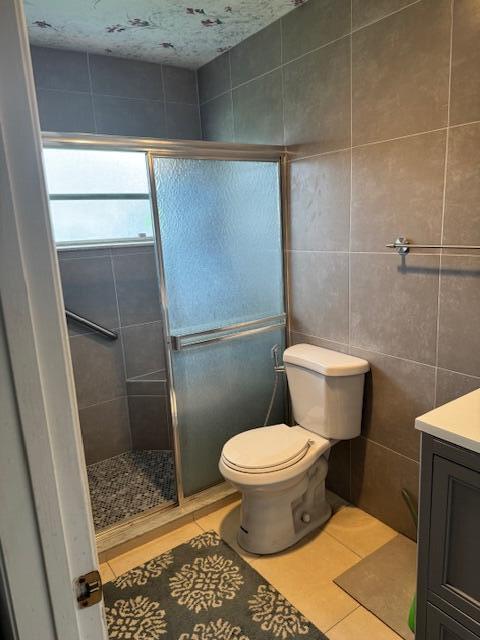 5397 Lakefront Blvd Unit A, Delray Beach, FL 33484 - bathroom featuring tile patterned flooring, tile walls, a shower stall, vanity, and toilet