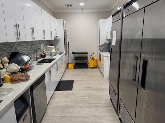 5397 Lakefront Blvd Unit A, Delray Beach, FL 33484 - kitchen with stainless steel appliances, a sink, white cabinets, crown molding, and light countertops