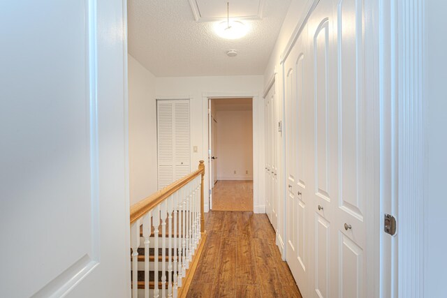 2641 Gately Dr W Unit 1003, West Palm Beach, FL 33415 - hallway featuring an upstairs landing, attic access, wood finished floors, baseboards, and a textured ceiling