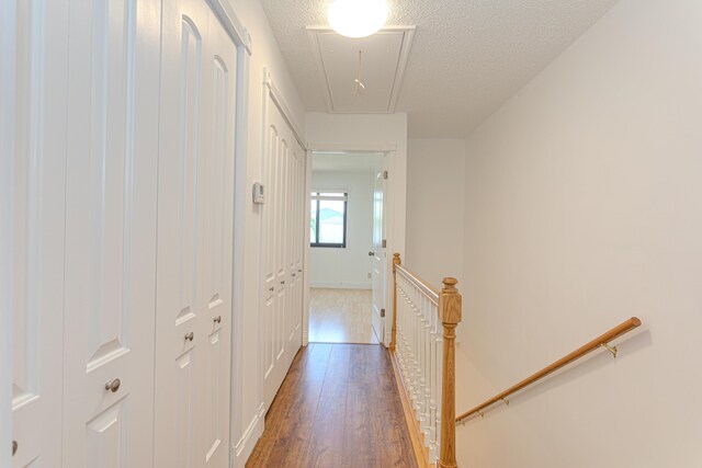 2641 Gately Dr W Unit 1003, West Palm Beach, FL 33415 - hallway featuring an upstairs landing, attic access, wood finished floors, baseboards, and a textured ceiling