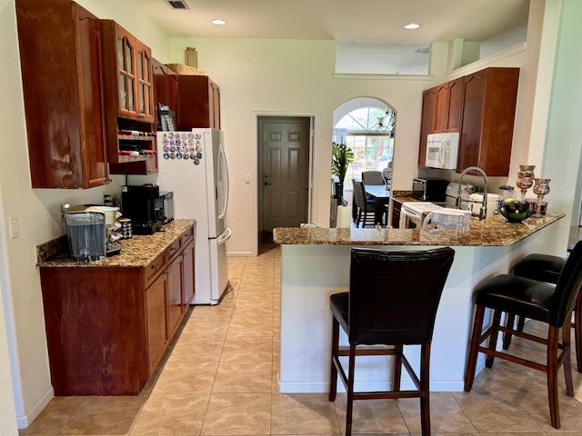 1710 SW Columbia St, Port Saint Lucie, FL 34987 - kitchen with white appliances, a kitchen breakfast bar, a peninsula, a sink, and stone counters