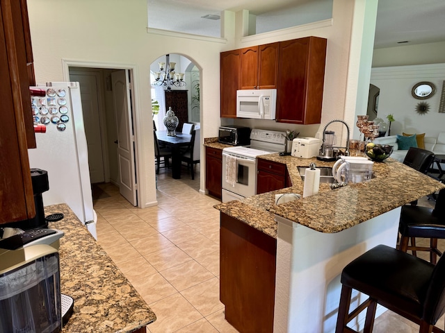 1710 SW Columbia St, Port Saint Lucie, FL 34987 - kitchen with white appliances, a chandelier, stone countertops, a breakfast bar, and a peninsula