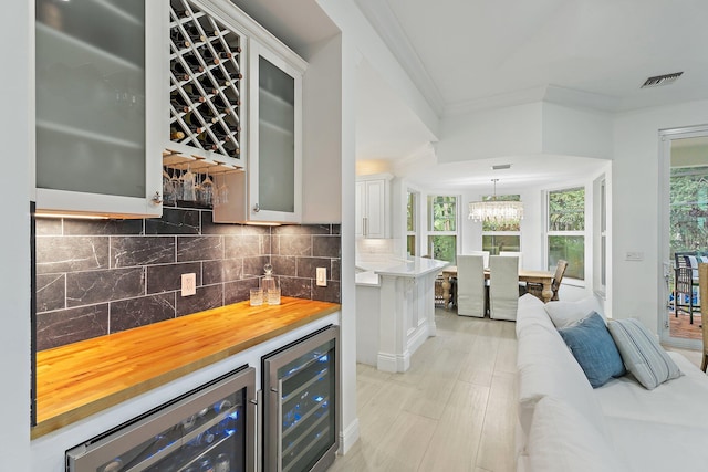 106 Henry Sewall Way, Sewalls Point, FL 34996 - indoor dry bar with beverage cooler, crown molding, decorative backsplash, hanging light fixtures, and a chandelier