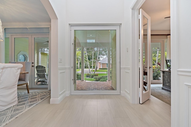 106 Henry Sewall Way, Sewalls Point, FL 34996 - foyer featuring a decorative wall, crown molding, arched walkways, and wainscoting
