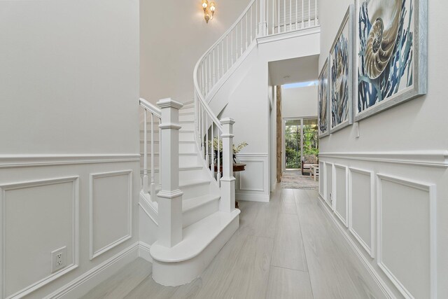 106 Henry Sewall Way, Sewalls Point, FL 34996 - foyer entrance with a decorative wall, stairway, a towering ceiling, and wainscoting