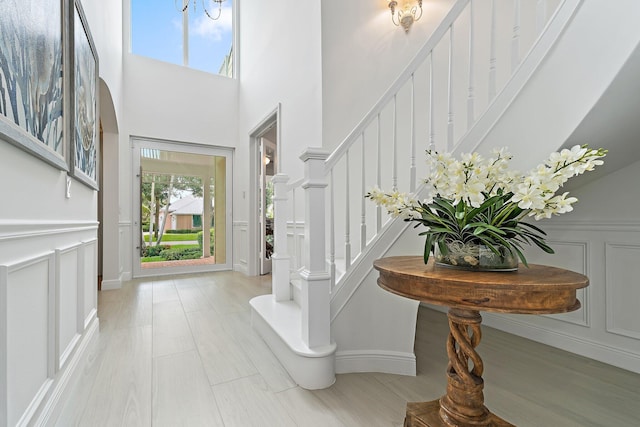 106 Henry Sewall Way, Sewalls Point, FL 34996 - foyer entrance with a decorative wall, stairway, a high ceiling, a wainscoted wall, and baseboards