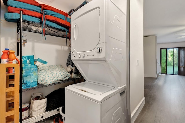 1232 W Club Dr W Unit D, Delray Beach, FL 33445 - laundry room featuring stacked washing machine and dryer, baseboards, and wood finished floors