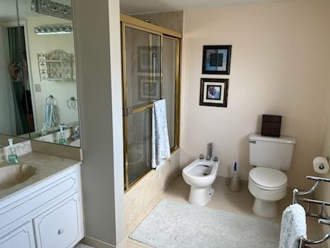 4200 S Ocean Blvd Unit 503, South Palm Beach, FL 33480 - full bathroom featuring a bidet, vanity, toilet, bath / shower combo with glass door, and baseboards