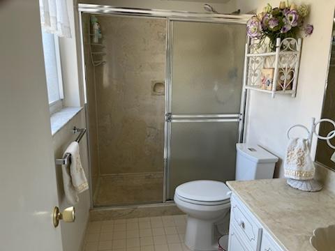 4200 S Ocean Blvd Unit 503, South Palm Beach, FL 33480 - bathroom featuring toilet, a stall shower, vanity, and tile patterned floors