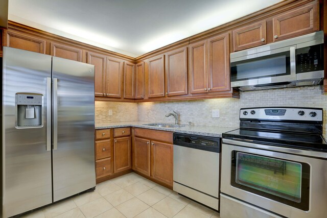 400 Ocean Trail Way Unit 707, Jupiter, FL 33477 - kitchen with appliances with stainless steel finishes, a sink, light tile patterned floors, and brown cabinetry