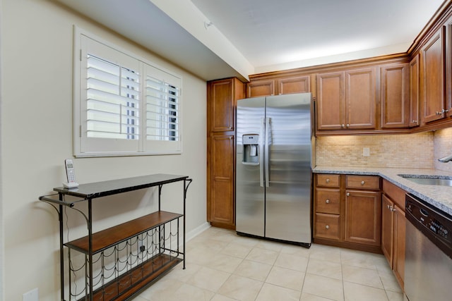 400 Ocean Trail Way Unit 707, Jupiter, FL 33477 - kitchen featuring appliances with stainless steel finishes, a sink, brown cabinets, backsplash, and light stone counters