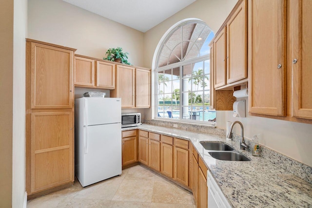 8351 Mastic Cay, West Palm Beach, FL 33411 - kitchen with freestanding refrigerator, stainless steel microwave, a sink, light stone countertops, and light brown cabinetry