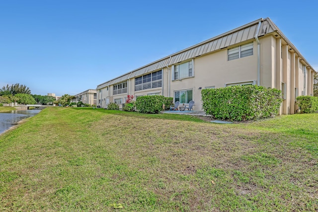 10789 N Military Trl Unit 3, Palm Beach Gardens, FL 33410 - back of house featuring stucco siding, a yard, and a water view