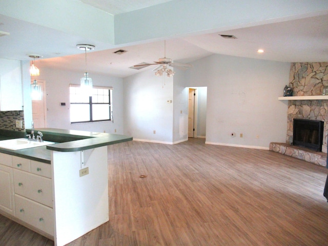 334 Brookedge Ter, Sebastian, FL 32958 - kitchen with a sink, dark countertops, open floor plan, white cabinetry, and a fireplace