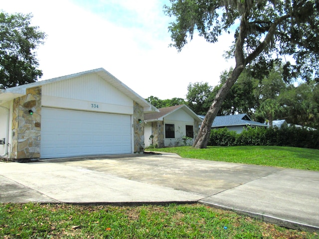 334 Brookedge Ter, Sebastian, FL 32958 - ranch-style house with stone siding, driveway, an attached garage, and a front yard