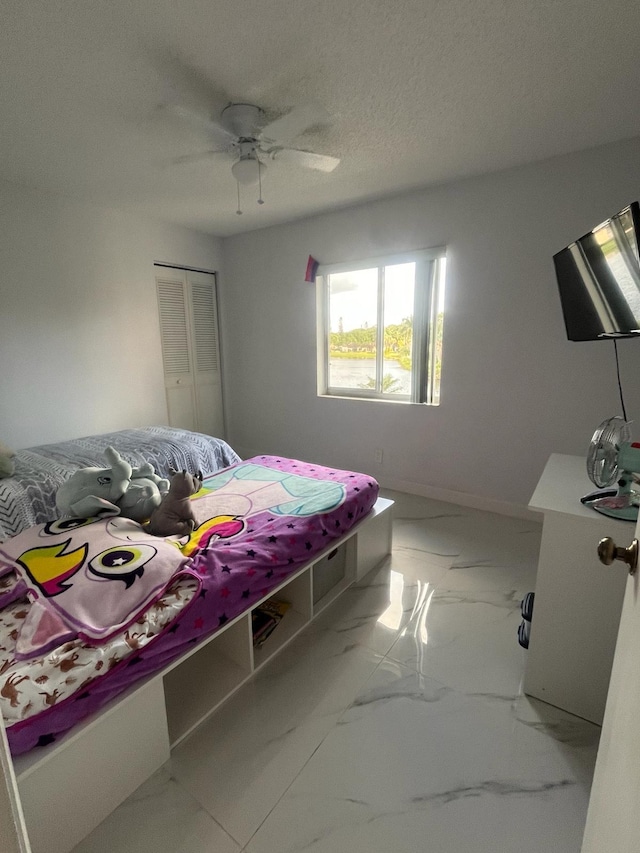 4988 Sable Pine Cir Unit B2, West Palm Beach, FL 33417 - bedroom featuring marble look tiles, ceiling fan, a closet, and a textured ceiling