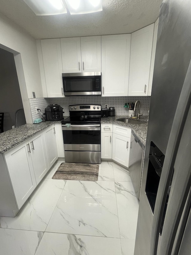 4988 Sable Pine Cir Unit B2, West Palm Beach, FL 33417 - kitchen featuring appliances with stainless steel finishes, light marble finish flooring, white cabinets, and stone counters