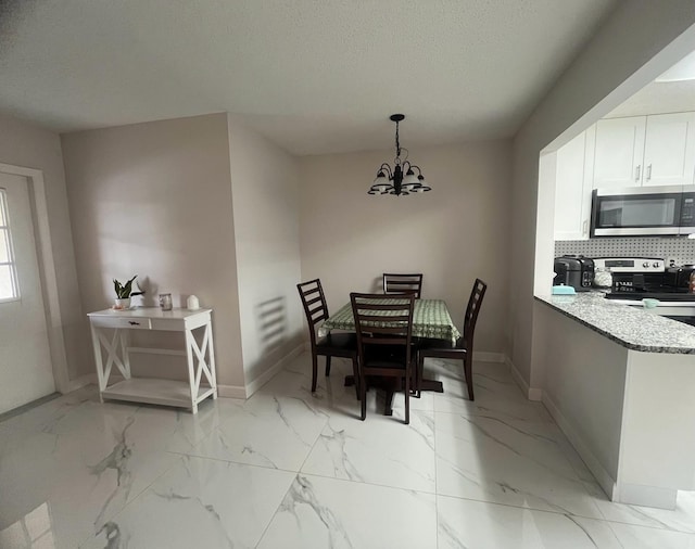 4988 Sable Pine Cir Unit B2, West Palm Beach, FL 33417 - dining room featuring baseboards, a chandelier, light marble finish flooring, and a textured ceiling