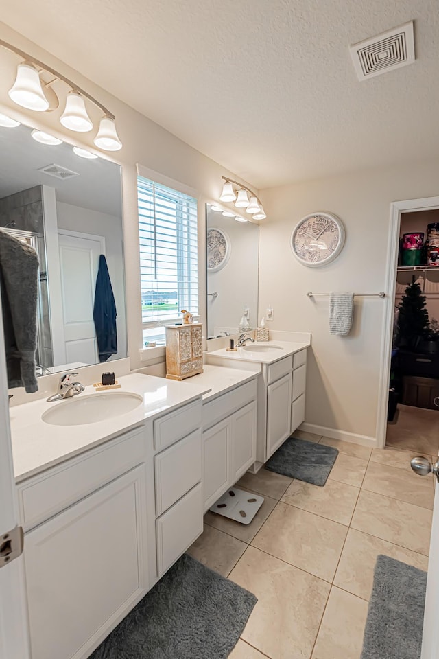 9351 SW Serapis Way, Port Saint Lucie, FL 34987 - full bathroom featuring double vanity, tile patterned flooring, a walk in closet, a textured ceiling, and a shower