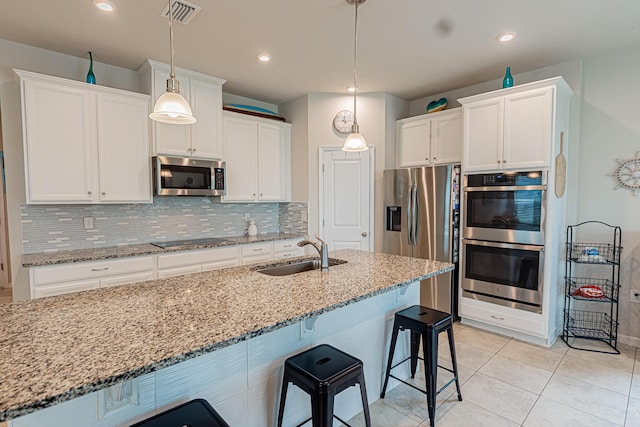 9351 SW Serapis Way, Port Saint Lucie, FL 34987 - kitchen with stainless steel appliances, a sink, a kitchen bar, backsplash, and recessed lighting