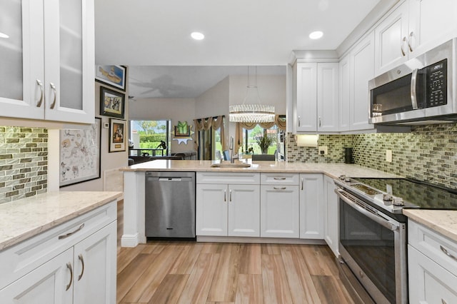 8178 Mooring Cir, Boynton Beach, FL 33472 - kitchen with appliances with stainless steel finishes, a sink, white cabinets, light wood-type flooring, and decorative backsplash