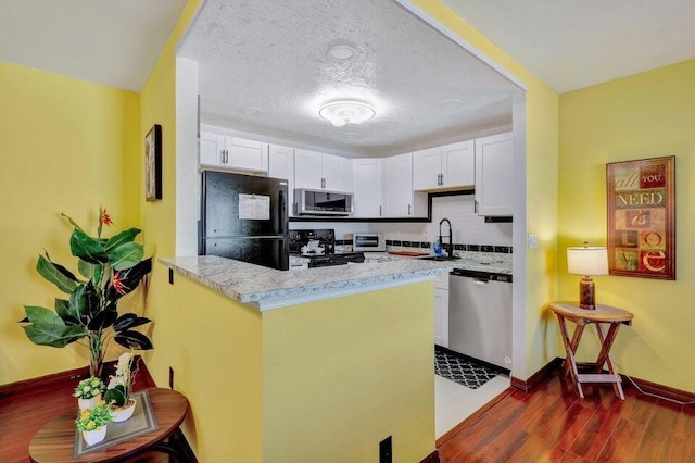 278 Monaco Way Unit F, Delray Beach, FL 33446 - kitchen with black appliances, dark wood finished floors, white cabinetry, a sink, and baseboards