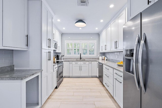 215 Cortez Rd, West Palm Beach, FL 33405 - kitchen featuring appliances with stainless steel finishes, decorative backsplash, recessed lighting, stone counters, and white cabinets