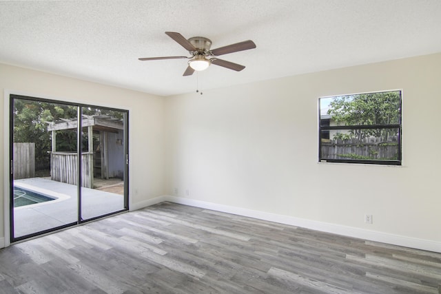 5666 SE Matousek St, Stuart, FL 34997 - unfurnished room with wood finished floors, baseboards, ceiling fan, and a textured ceiling