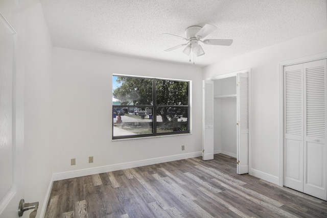 5666 SE Matousek St, Stuart, FL 34997 - unfurnished bedroom featuring multiple closets, wood finished floors, a textured ceiling, baseboards, and a ceiling fan