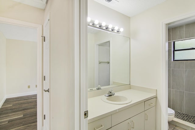 5666 SE Matousek St, Stuart, FL 34997 - full bath featuring toilet, vanity, tiled shower, and wood finished floors