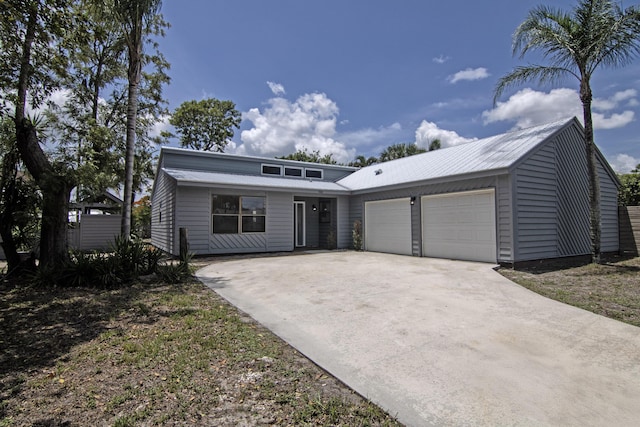 5666 SE Matousek St, Stuart, FL 34997 - mid-century modern home featuring an attached garage, metal roof, and driveway