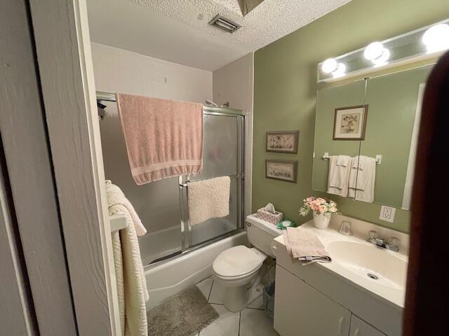 108 SW 18th St, Boynton Beach, FL 33426 - full bathroom featuring vanity, toilet, a textured ceiling, combined bath / shower with glass door, and tile patterned flooring
