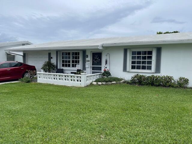 108 SW 18th St, Boynton Beach, FL 33426 - single story home with an attached garage, covered porch, a front yard, and stucco siding