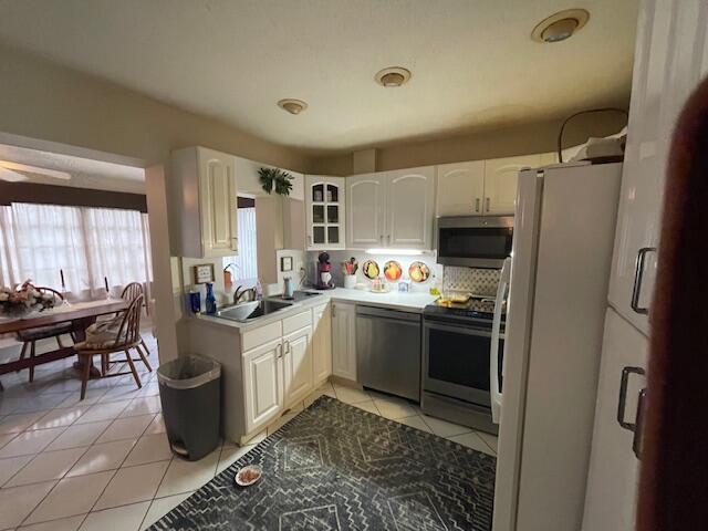 108 SW 18th St, Boynton Beach, FL 33426 - kitchen with stainless steel appliances, light tile patterned flooring, a sink, glass insert cabinets, and white cabinets