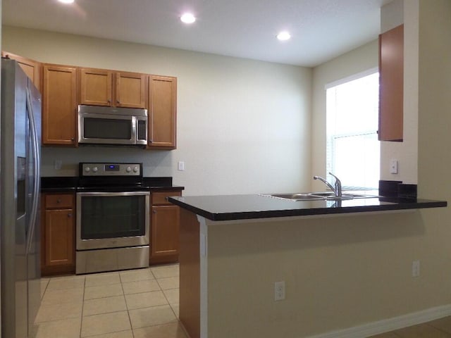 328 Lake Monterey Cir, Boynton Beach, FL 33426 - kitchen featuring appliances with stainless steel finishes, a sink, a peninsula, dark countertops, and brown cabinetry