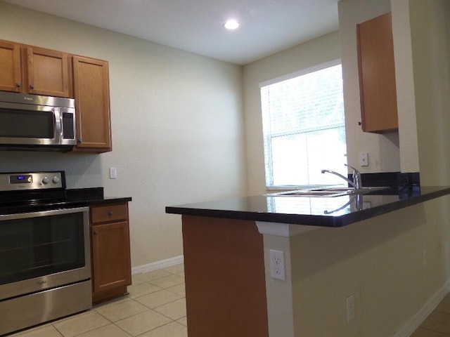 328 Lake Monterey Cir, Boynton Beach, FL 33426 - kitchen with appliances with stainless steel finishes, a peninsula, brown cabinets, baseboards, and dark countertops