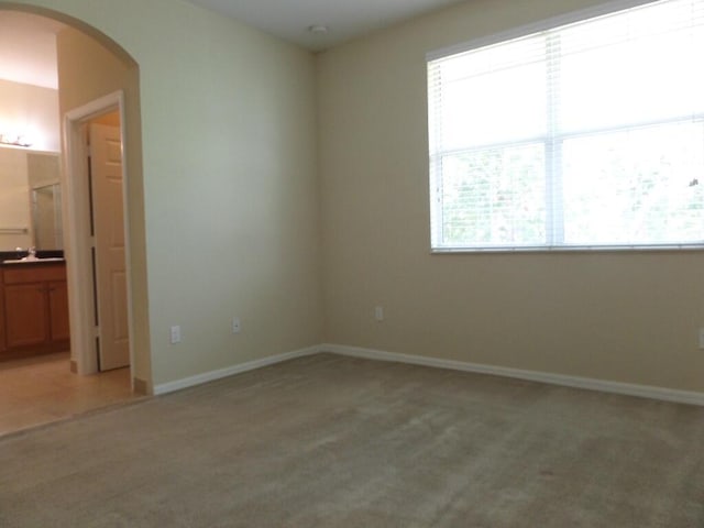 328 Lake Monterey Cir, Boynton Beach, FL 33426 - unfurnished bedroom with arched walkways, light colored carpet, multiple windows, and baseboards