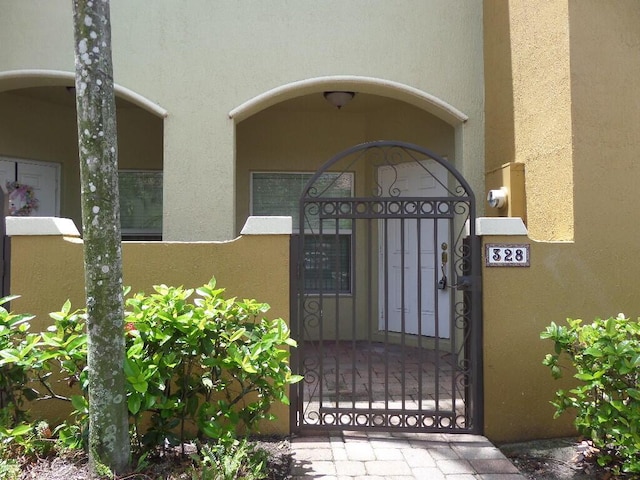 328 Lake Monterey Cir, Boynton Beach, FL 33426 - view of exterior entry with a gate and stucco siding