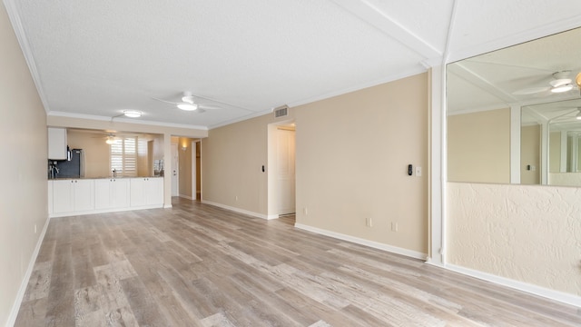 1950 SW Palm City Rd Unit 8302, Stuart, FL 34994 - unfurnished living room featuring a ceiling fan, crown molding, light wood finished floors, baseboards, and a textured ceiling