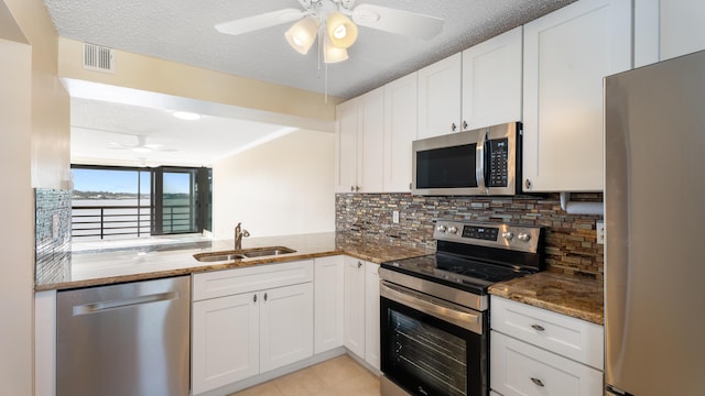 1950 SW Palm City Rd Unit 8302, Stuart, FL 34994 - kitchen featuring appliances with stainless steel finishes, a sink, ceiling fan, dark stone countertops, and a textured ceiling