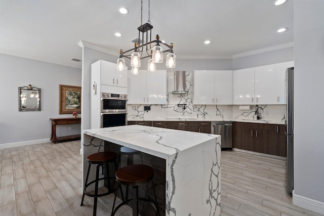 979 SW Mcdevitt Ave, Port Saint Lucie, FL 34953 - kitchen with stainless steel appliances, wall chimney exhaust hood, white cabinets, baseboards, and ornamental molding