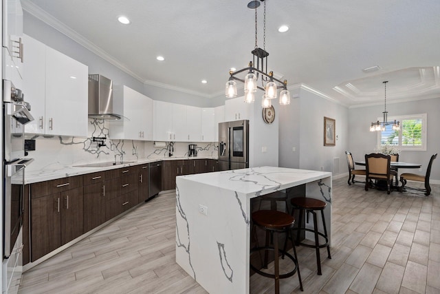 979 SW Mcdevitt Ave, Port Saint Lucie, FL 34953 - kitchen featuring appliances with stainless steel finishes, wall chimney exhaust hood, a chandelier, a kitchen island, and dark brown cabinetry