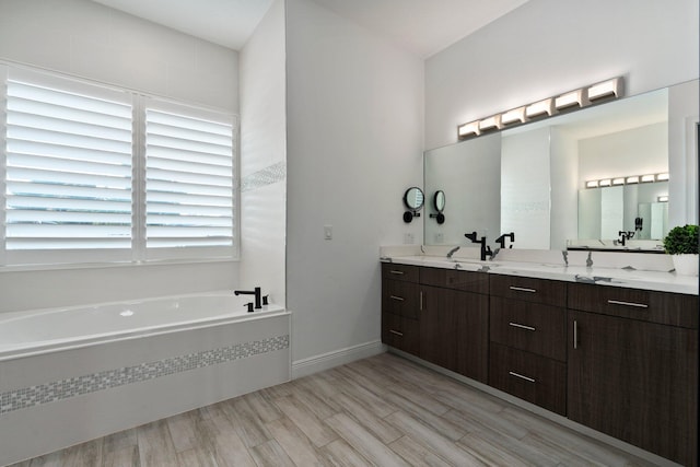 979 SW Mcdevitt Ave, Port Saint Lucie, FL 34953 - full bathroom featuring double vanity, a garden tub, wood finished floors, and baseboards