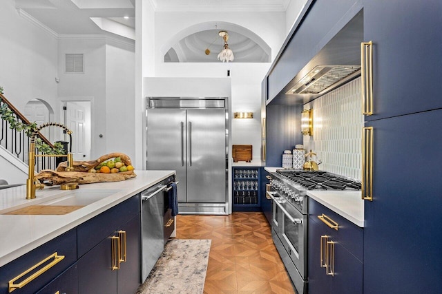 107 SE Santa Gardenia, Port Saint Lucie, FL 34984 - kitchen featuring high quality appliances, blue cabinets, wall chimney range hood, a sink, and crown molding