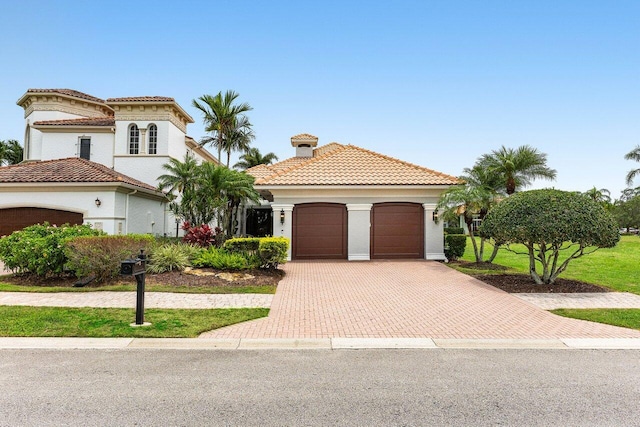 107 SE Santa Gardenia, Port Saint Lucie, FL 34984 - mediterranean / spanish-style home with an attached garage, decorative driveway, a tiled roof, stucco siding, and a chimney