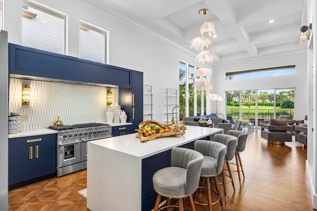 107 SE Santa Gardenia, Port Saint Lucie, FL 34984 - kitchen featuring range with two ovens, blue cabinets, a kitchen bar, light countertops, and a towering ceiling