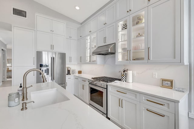 202 Isle Verde Way, Palm Beach Gardens, FL 33418 - kitchen featuring under cabinet range hood, appliances with stainless steel finishes, a sink, glass insert cabinets, and lofted ceiling