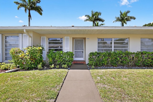 8644 Boca Dr, Boca Raton, FL 33433 - doorway to property with a lawn and stucco siding