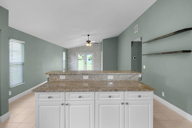 2867 SW Mustang Ter, Stuart, FL 34997 - kitchen featuring lofted ceiling, a ceiling fan, light tile patterned floors, light stone countertops, and white cabinets