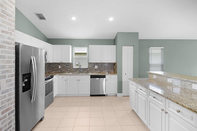 2867 SW Mustang Ter, Stuart, FL 34997 - kitchen featuring stainless steel appliances, tasteful backsplash, lofted ceiling, light stone countertops, and white cabinetry